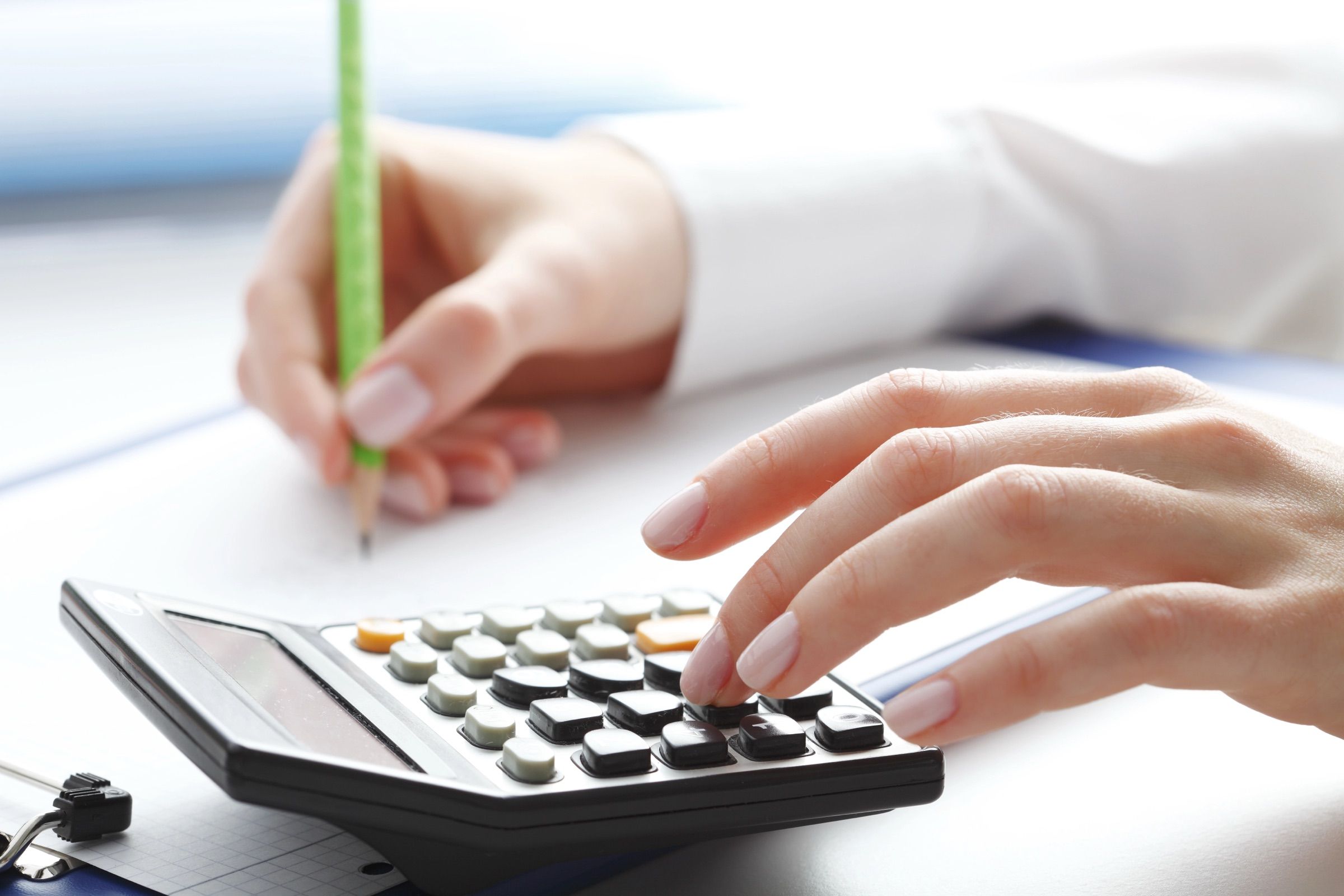 Mâini care lucrează cu un calculator și un pix